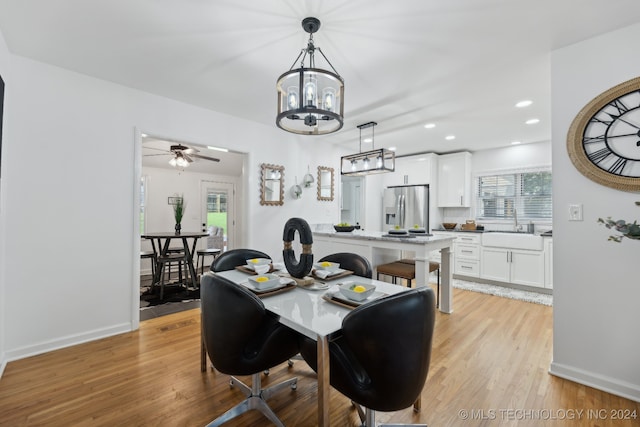 dining room featuring plenty of natural light, sink, ceiling fan with notable chandelier, and light hardwood / wood-style flooring