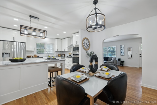 dining area with an inviting chandelier, light hardwood / wood-style flooring, and sink