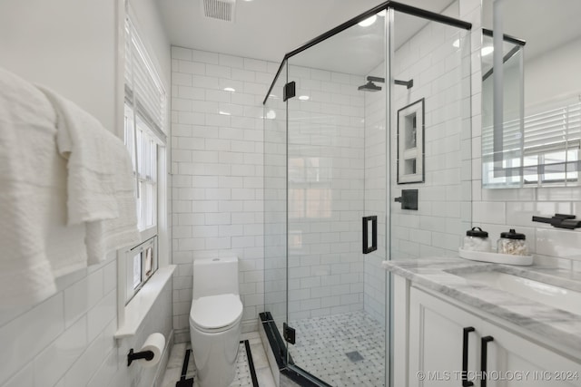 bathroom with an enclosed shower, toilet, tile walls, and a wealth of natural light