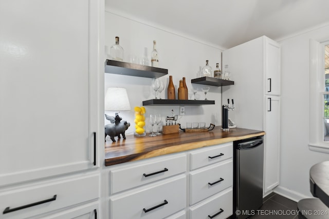 kitchen featuring dark tile patterned floors, white cabinets, and wood counters