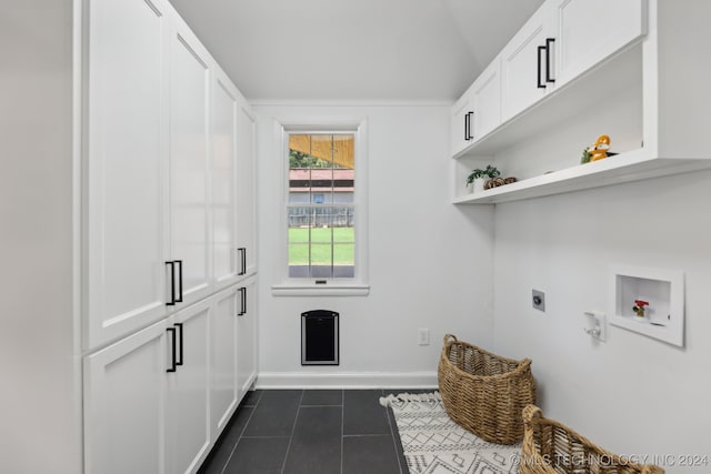 washroom with washer hookup, cabinets, dark tile patterned flooring, and hookup for an electric dryer