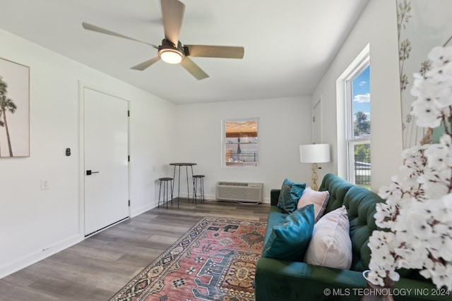 living area featuring a wall mounted AC, hardwood / wood-style flooring, and ceiling fan