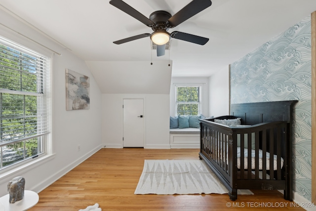 bedroom featuring multiple windows, ceiling fan, hardwood / wood-style floors, and a nursery area