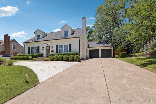 new england style home featuring a front lawn and a garage