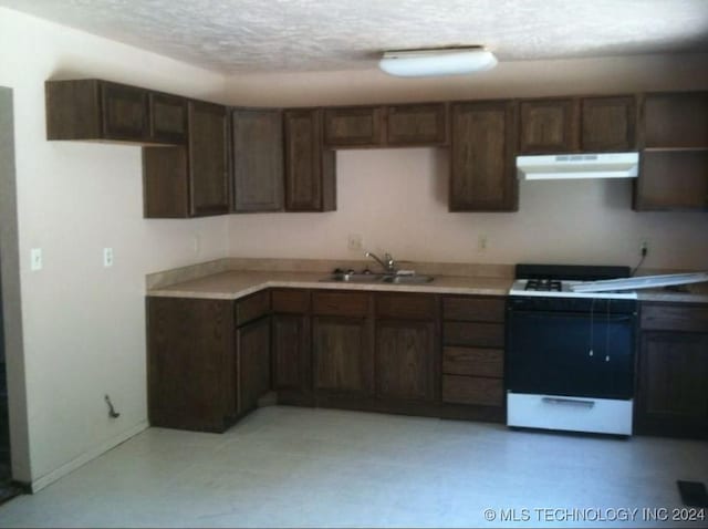 kitchen featuring a textured ceiling, white range, dark brown cabinets, and sink