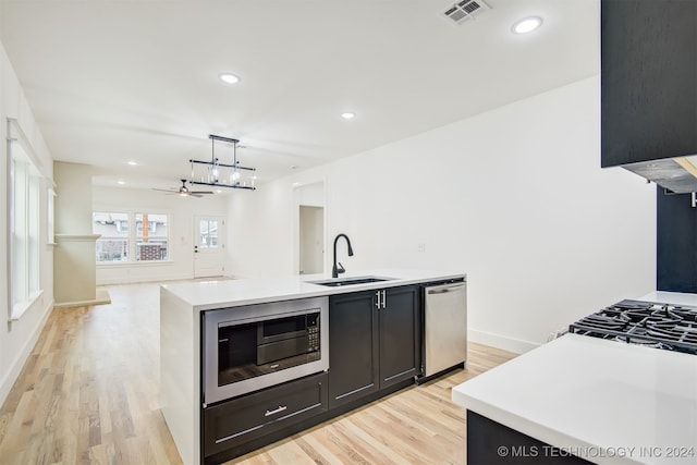 kitchen featuring ceiling fan, sink, stainless steel appliances, pendant lighting, and a center island with sink