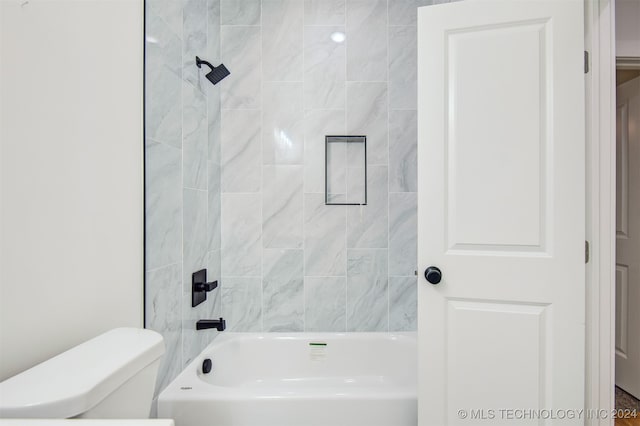 bathroom featuring tiled shower / bath combo and toilet