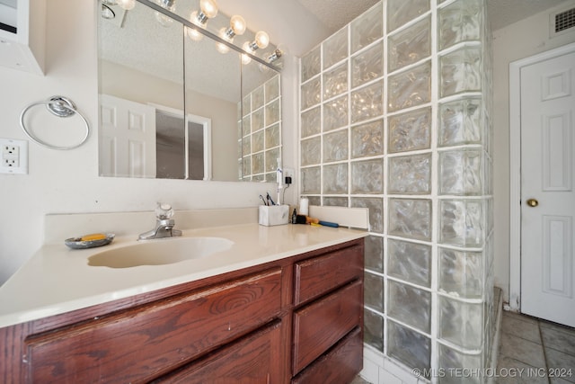 bathroom featuring tile patterned floors, vanity, a textured ceiling, and walk in shower