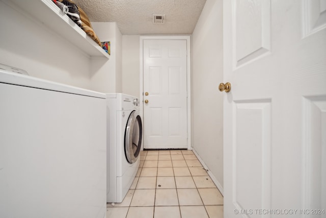 laundry room with light tile patterned floors, a textured ceiling, and washer / clothes dryer