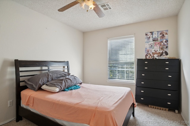 bedroom with ceiling fan, light colored carpet, and a textured ceiling