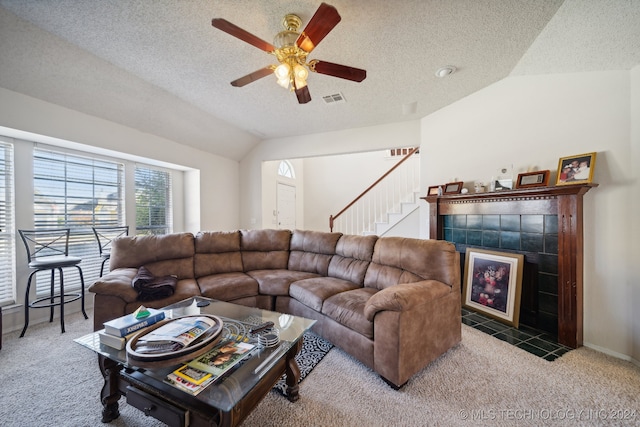 carpeted living room with a textured ceiling, ceiling fan, a fireplace, and vaulted ceiling