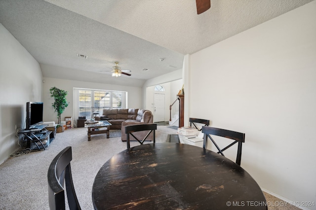 carpeted dining space featuring lofted ceiling, ceiling fan, and a textured ceiling