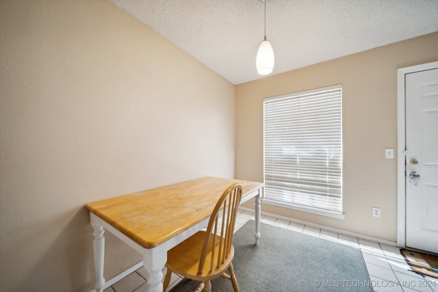 dining room featuring light tile patterned flooring, a textured ceiling, and vaulted ceiling