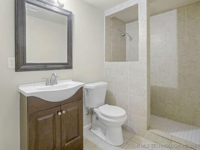 bathroom featuring tiled shower, vanity, toilet, and tile patterned flooring