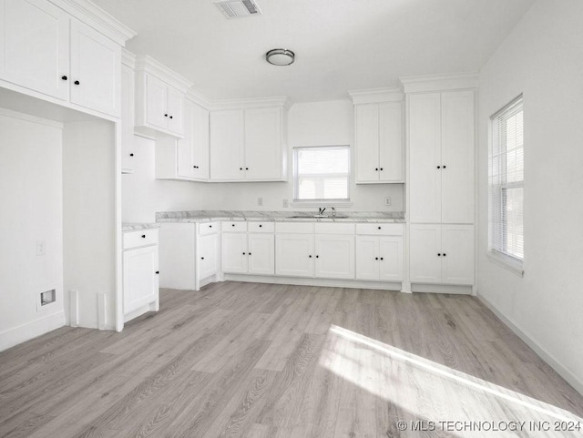 kitchen with light wood-type flooring, white cabinetry, and sink