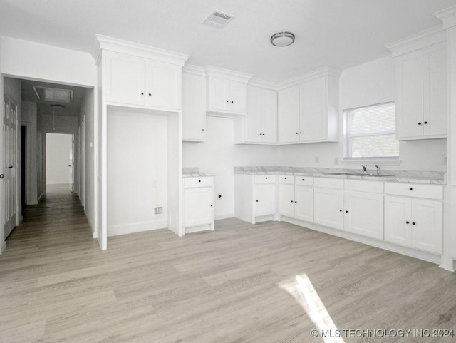 kitchen featuring light stone counters, sink, light hardwood / wood-style floors, and white cabinets