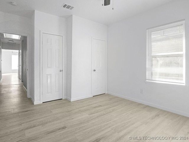 unfurnished bedroom with ceiling fan, multiple windows, and light hardwood / wood-style flooring