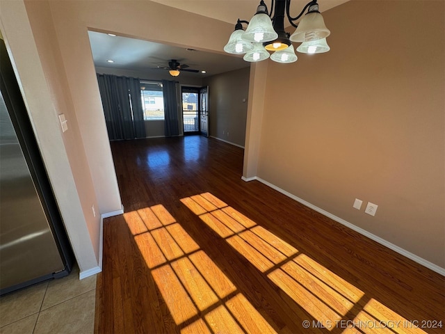 unfurnished dining area with hardwood / wood-style flooring and ceiling fan with notable chandelier