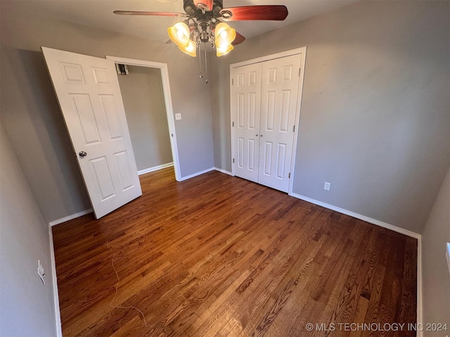 unfurnished bedroom featuring ceiling fan, dark hardwood / wood-style flooring, and a closet