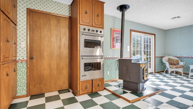 kitchen featuring double oven, a wood stove, decorative light fixtures, and a textured ceiling