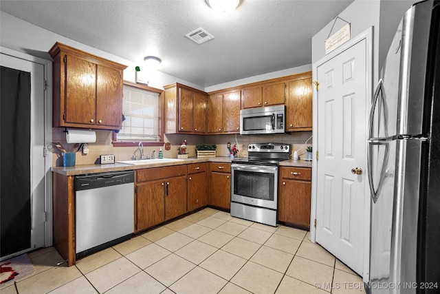 kitchen featuring decorative backsplash, appliances with stainless steel finishes, light tile patterned floors, and sink