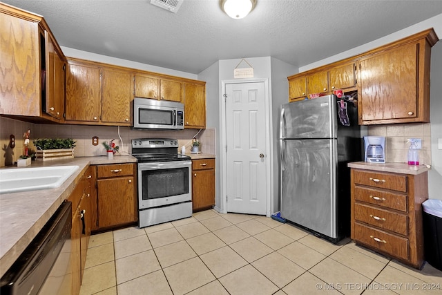 kitchen featuring a textured ceiling, decorative backsplash, sink, and stainless steel appliances