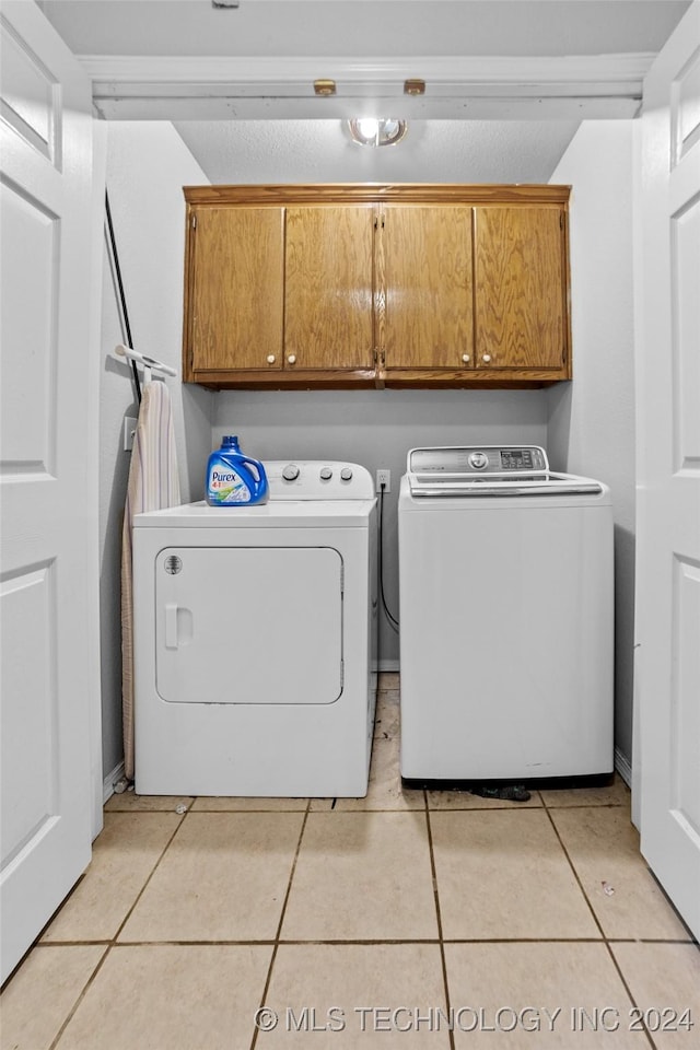 laundry room featuring cabinets, light tile patterned floors, and separate washer and dryer