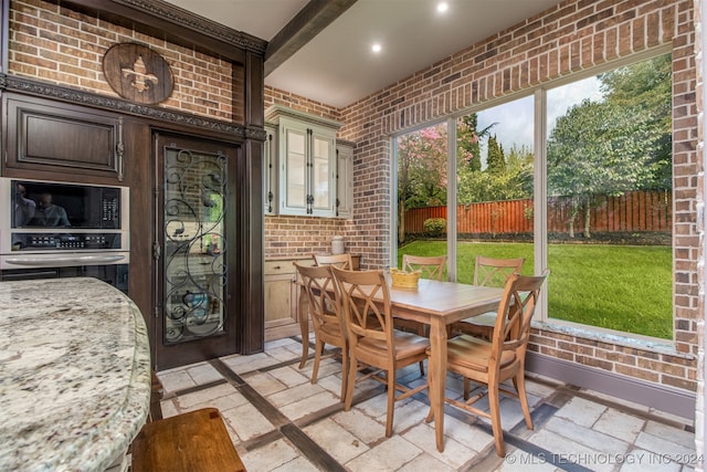 dining area with beamed ceiling and brick wall