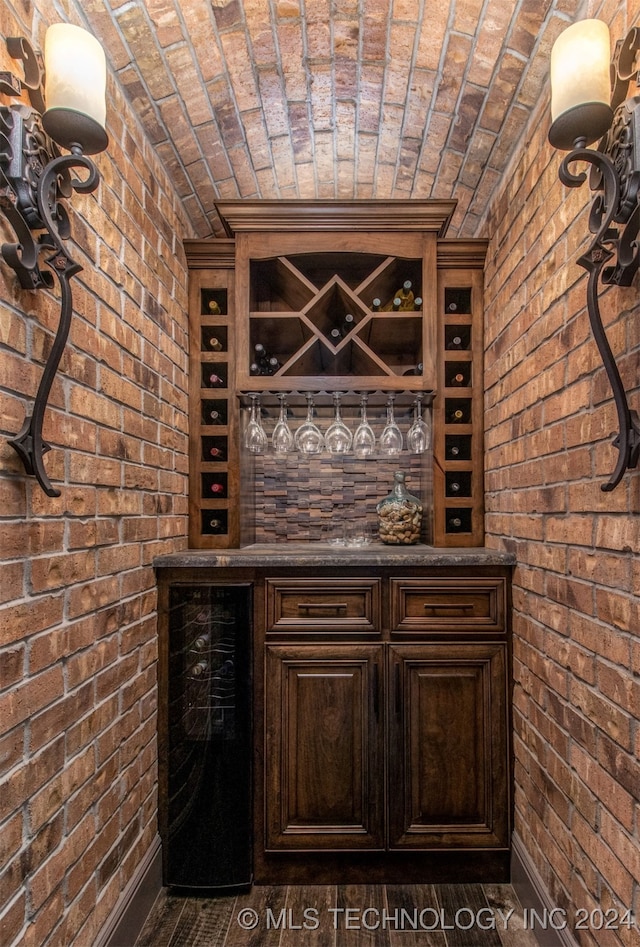 wine area with brick wall, brick ceiling, and wine cooler