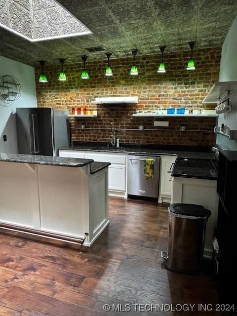 bar with white cabinetry, stainless steel appliances, brick wall, dark hardwood / wood-style floors, and dark stone countertops