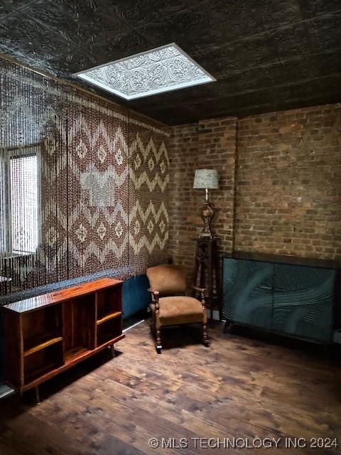 living area featuring hardwood / wood-style flooring and brick wall