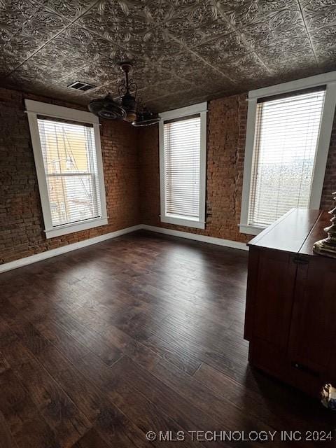 unfurnished dining area with brick wall and dark hardwood / wood-style floors