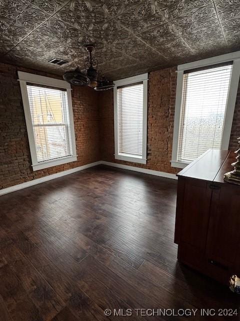 8 W Main St, Ardmore, OK 73401 - unfurnished dining area with an ornate ceiling, brick wall, a chandelier, and dark wood-style flooring