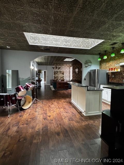 kitchen featuring stainless steel fridge, white cabinets, and dark wood-type flooring