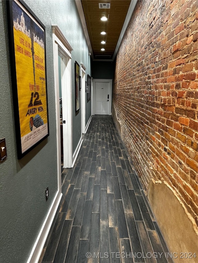 hallway with brick wall and dark hardwood / wood-style floors