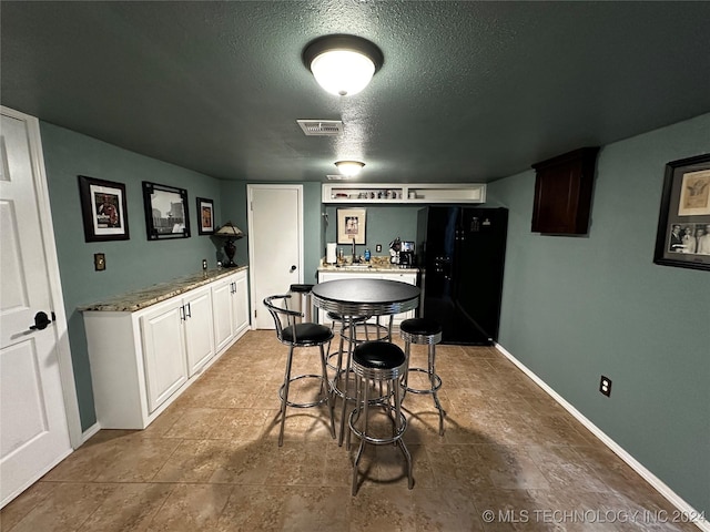 dining room featuring a textured ceiling and indoor bar