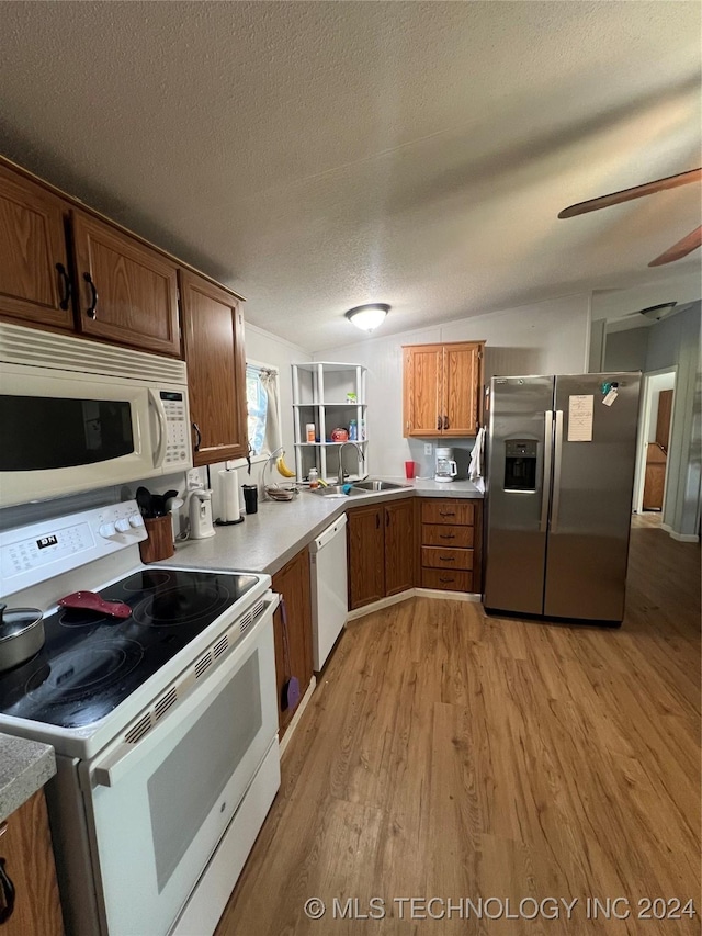 kitchen featuring light hardwood / wood-style floors, sink, white appliances, and a textured ceiling