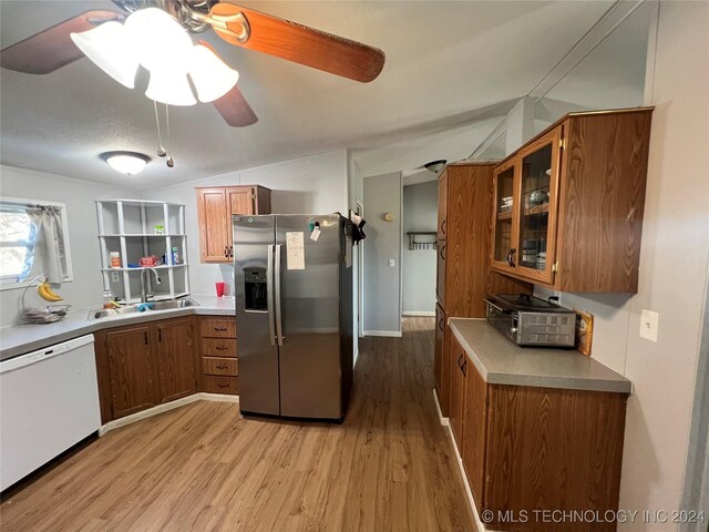 kitchen featuring sink, stainless steel fridge with ice dispenser, white dishwasher, light hardwood / wood-style floors, and lofted ceiling