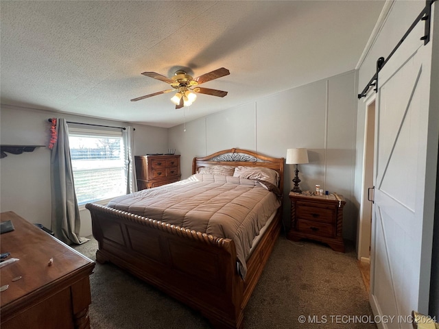 carpeted bedroom featuring a barn door, ceiling fan, and a textured ceiling