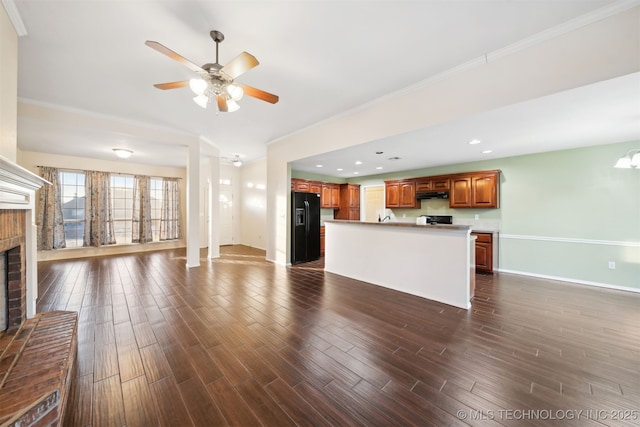 unfurnished living room featuring crown molding, ceiling fan, and a brick fireplace