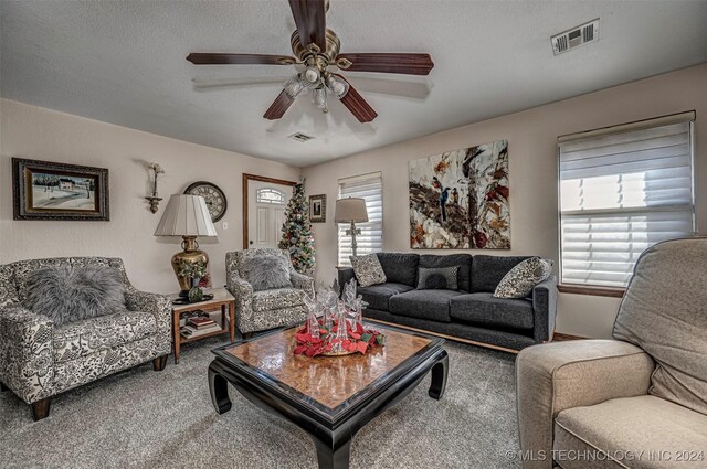 carpeted living room featuring ceiling fan and a textured ceiling