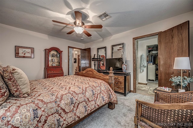 bedroom featuring a walk in closet, a textured ceiling, light colored carpet, ceiling fan, and a closet