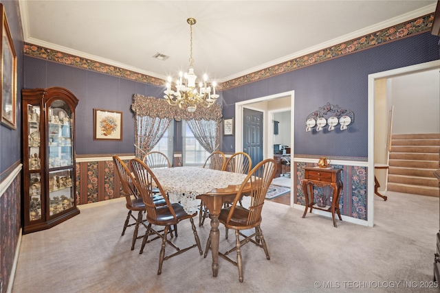 dining space with crown molding, carpet floors, and an inviting chandelier