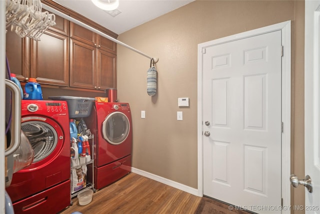 clothes washing area with cabinets, washing machine and clothes dryer, and dark wood-type flooring