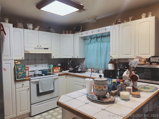 kitchen featuring white cabinets, tile counters, electric stove, and sink