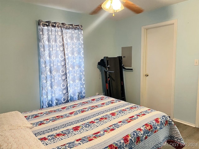 bedroom with hardwood / wood-style floors, electric panel, and ceiling fan