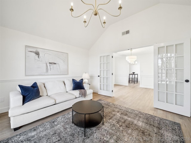 living room featuring a notable chandelier, wood-type flooring, high vaulted ceiling, and french doors