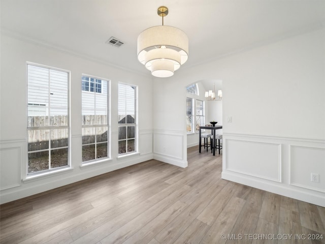 unfurnished dining area with plenty of natural light, light wood-type flooring, and an inviting chandelier