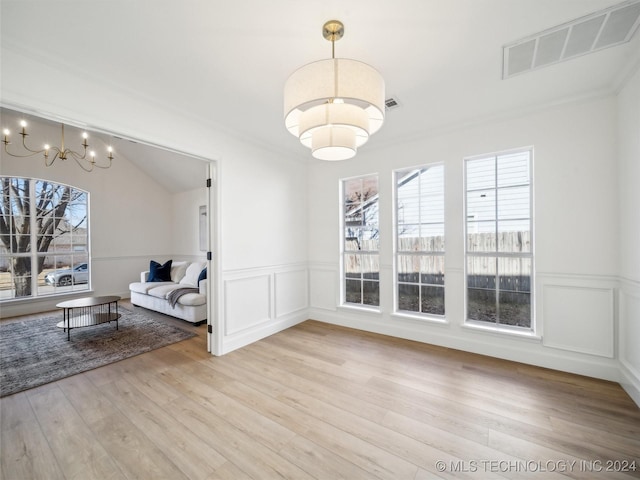 dining room featuring light wood-type flooring, vaulted ceiling, and a notable chandelier