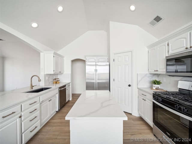 kitchen with sink, white cabinets, stainless steel appliances, and vaulted ceiling